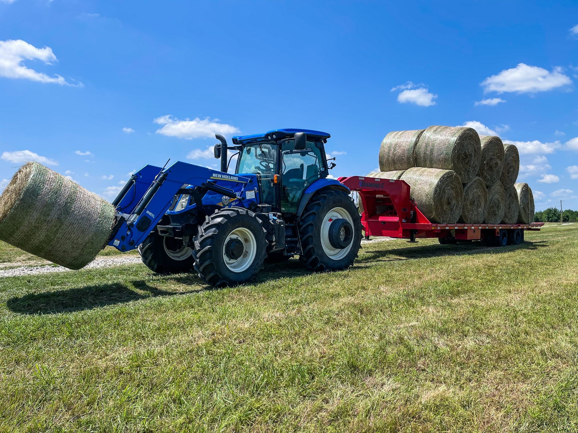tractor pulling round bales from a field